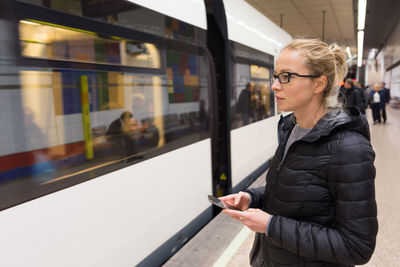 Mid adult woman using mobile phone while standing on bus