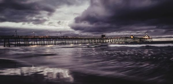Pier over sea against sky at sunset