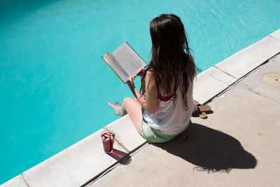 High angle view of woman reading book at poolside