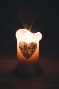 Close-up of burning candle against black background