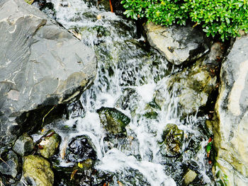 High angle view of stream flowing through rocks