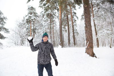 A young man with a snowball in his hand is having fun, swinging for a throw. winter family 