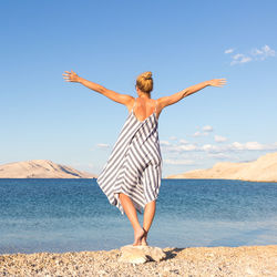 Full length of young woman at beach against sky