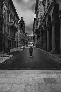 Woman standing on road amidst buildings in city