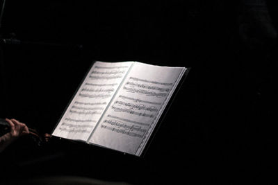 Close-up of hand holding guitar against black background