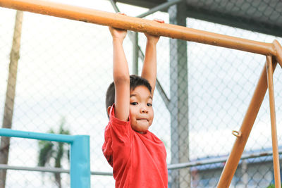 Boy hanging on metal in playground
