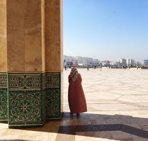 Rear view of woman standing at mosque against sky