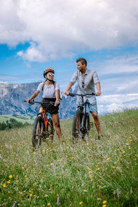 Woman with bicycle on field against sky