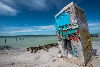 Graffiti on beach against sky