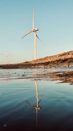 Wind turbines on land against clear sky