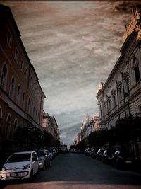 Cars on street in city against sky