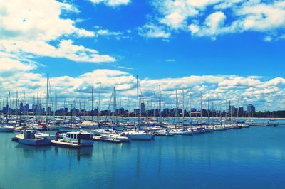 Boats in harbor against cloudy sky