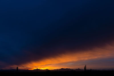 Scenic view of dramatic sky over silhouette landscape during sunset