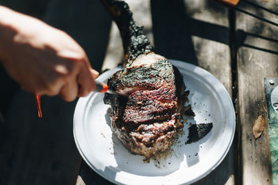 Close-up of hand holding meat on barbecue grill