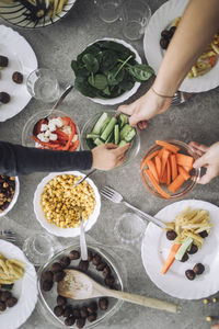 Directly above view of students passing food bowls during lunch time at dining table