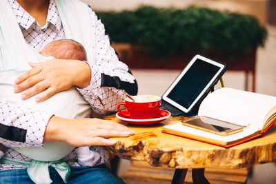 Midsection of woman using smart phone while sitting at table