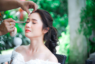 Close-up of person applying make-up on woman face