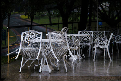 Empty chairs and tables against trees