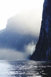 A waterfall and a tiny boat. lots of mist, high walls of rock. bright light and cold temperatures.