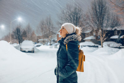 Woman in blue jacket winter clothes and hat walking outdoors under snow. winter romantic wonderland.