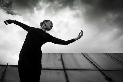 Low angle view of boy against cloudy sky