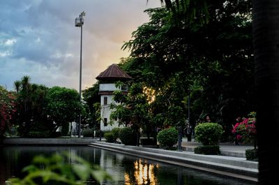 Street by lake and trees against sky