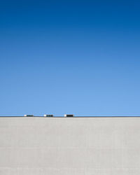 Low angle view of power lines against clear blue sky