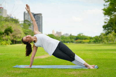 Side view of woman exercising on field