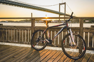 Bicycle on pier against sky during sunset