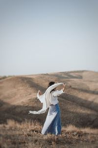 Full length of woman standing on field against clear sky