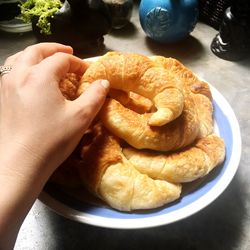 High angle view of person holding bread in plate on table