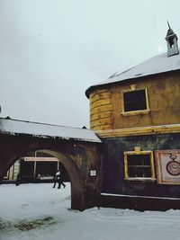 Low angle view of snow covered old building against sky