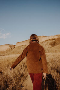 Rear view of man standing on field against clear sky