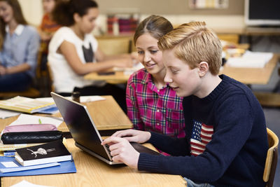 School students using laptop in classroom
