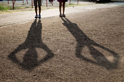 Low section of man with shadow on road