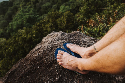 Low section of man relaxing on rock