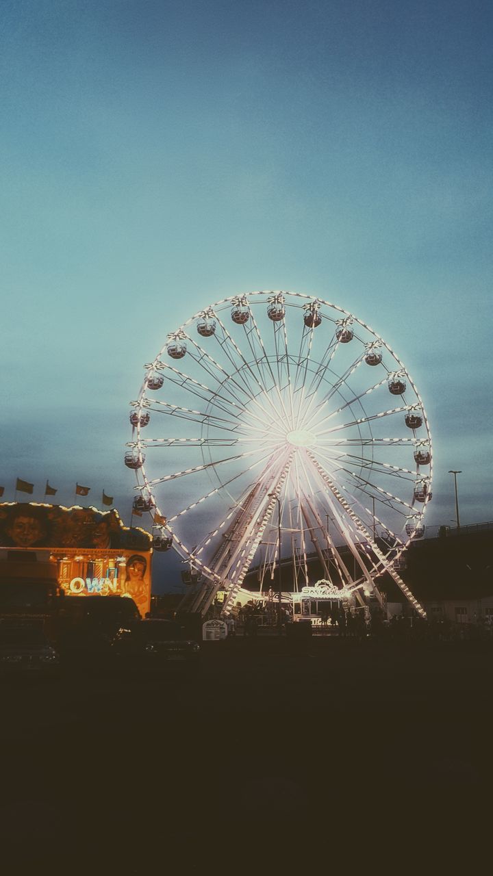 LOW ANGLE VIEW OF ILLUMINATED FERRIS WHEEL AGAINST BLUE SKY