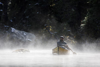 Rear view of man sitting on riverbank