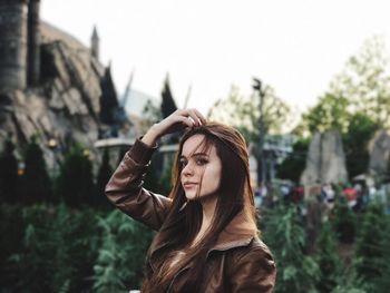 Close-up of young woman against trees against sky