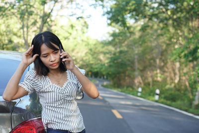 Young woman standing on road against trees