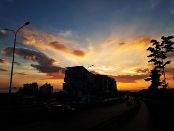 Cars on road against dramatic sky during sunset