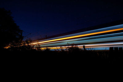 Blurred motion of illuminated train against sky at night