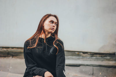 Portrait of beautiful young woman standing against wall