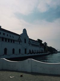 Building by sea against cloudy sky