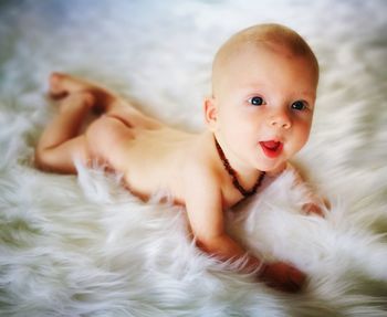 High angle view of naked baby lying on fur rug at home