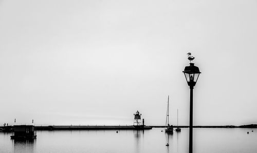 Street light by sea against clear sky