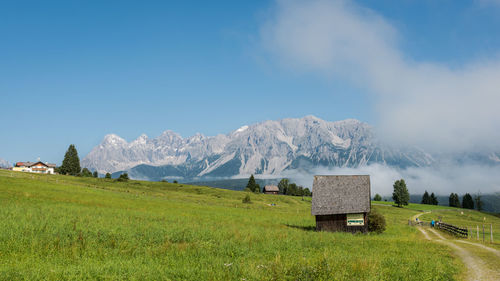 Hut on grassy field against mountains