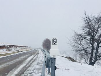 Stone mileage sign on a deserted road covered in snow during winter