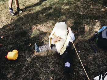 High angle view of boy covering face with towel while sitting on field