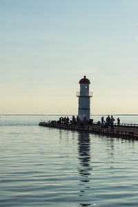 Lighthouse by sea against sky